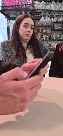 a woman sitting at a bar looking at a cell phone