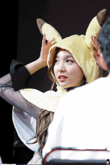 a woman wearing a pikachu costume has her hands on her hair