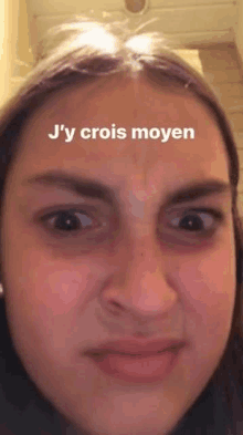 a close up of a woman 's face with the words `` j 'y crois moyen '' on her forehead .