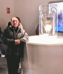 a man stands in front of a trophy that says uefa champions league