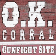 a red wooden sign with white letters that says ok corral gunfight site .