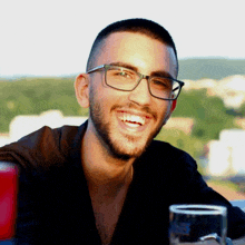 a man wearing glasses is smiling and holding a glass