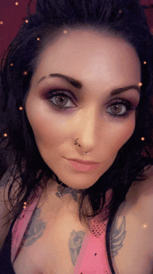 a close up of a woman 's face with a nose ring and tattoos