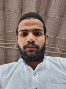 a man with a beard wears a white shirt and a black headband