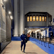 a man in a blue jacket is walking down a walkway in front of a building with a sign that says tower