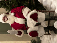 a man dressed as santa claus is sitting in a chair in front of a christmas tree