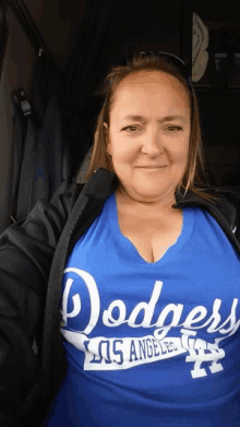 a woman wearing a blue dodgers t-shirt is smiling