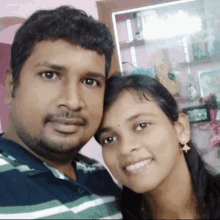 a man and a woman are posing for a picture and the woman is wearing earrings