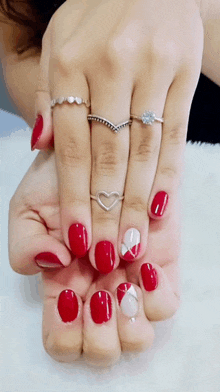 a close up of a woman 's hand with red nails and rings on her fingers