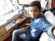 a young man sits in front of a desk with a stack of books on it including one titled ix