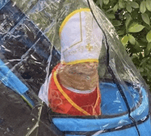 a cat wearing a bishop costume is sitting in a stroller .