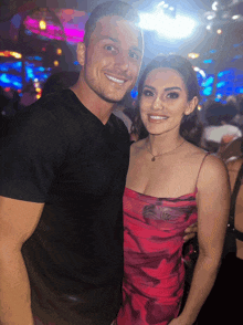 a man in a black shirt and a woman in a red dress are posing for a picture