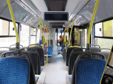 the inside of an empty bus with blue seats and yellow railings