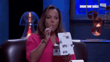 a woman is sitting on a couch with a box of food in front of a sign that says shark tank brasil on it