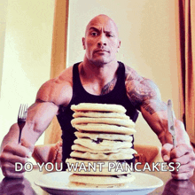 a man sitting at a table with a plate of pancakes and a fork and knife