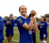 a female soccer player wearing a blue jersey with a patch on the sleeve that says ' champions league '