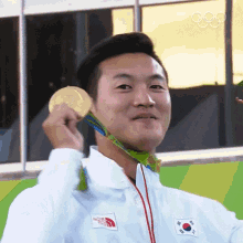 a man wearing a white jacket with the north face logo on it is holding a gold medal around his neck