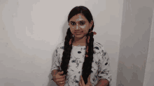 a young girl with long braids is standing in front of a wall