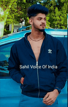 a man in a blue adidas jacket stands in front of a car