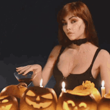 a woman in a witch costume is holding a martini in front of pumpkins and candles