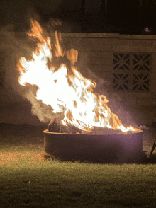 a fire is burning in a fire pit with a brick wall behind it