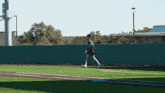 a person walking on a baseball field with a fence in the background and a sign that says ' a & m '