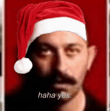 a man wearing a santa hat with the words " haha yes " below him