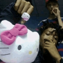 a man is holding a hello kitty stuffed animal with a pink bow on it .