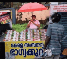 a man is sitting under an umbrella in front of a display of snacks