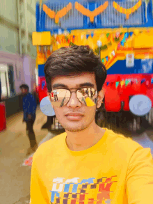 a young man wearing sunglasses and a yellow shirt that says ' dirty ' on it