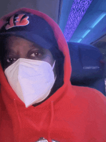 a person wearing a red hoodie and a face mask with a comfort seat in the background