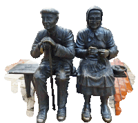 a statue of an elderly couple sits on a bench