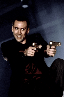 a man in a black shirt is holding two guns in his hands