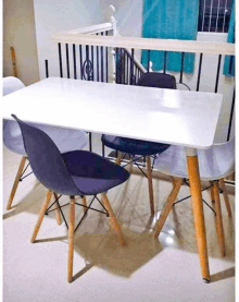 a white dining table with four chairs in a living room next to a balcony .