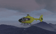 a yellow helicopter with a blue stripe on the tail flies over a mountain range