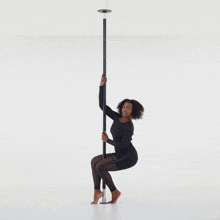 a woman is sitting on a pole in a black dress