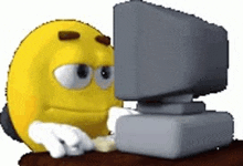 a yellow smiley face is sitting at a desk in front of a computer monitor .