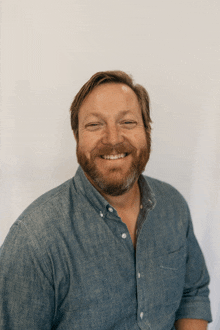 a man with a beard wearing a blue shirt smiles