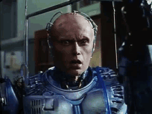 a man in a robot suit is standing in a room and looking at the camera with a surprised look on his face .