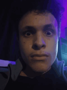 a close up of a person 's face with a purple light behind him