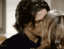 a man and a woman are kissing in a room on a television show .