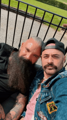 two men are posing for a picture with one wearing a denim jacket with a patch that says california