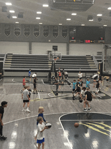 a group of kids are playing basketball in a gym with a scoreboard that shows the time as 4:04