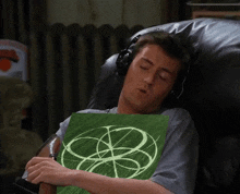 a man wearing headphones is sleeping in a chair while holding a green piece of paper