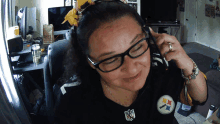 a woman wearing a pittsburgh steelers shirt is talking on a phone