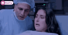 a man in a surgical gown is looking at a woman in a hospital bed .