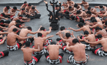 a group of men are kneeling in a circle with their arms outstretched in front of a candle holder