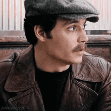 a man with a mustache wearing a hat and a leather jacket