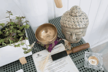 a buddha statue sits on a table next to a bowl and a piece of paper