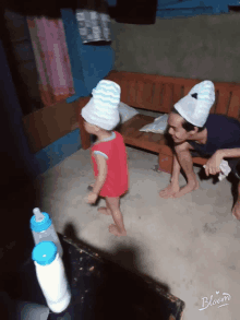 a baby wearing a towel on his head is standing next to a woman